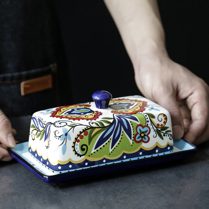 Colorful ceramic butter dish with floral patterns on a dark surface