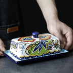 Colorful ceramic butter dish with floral patterns on a dark surface