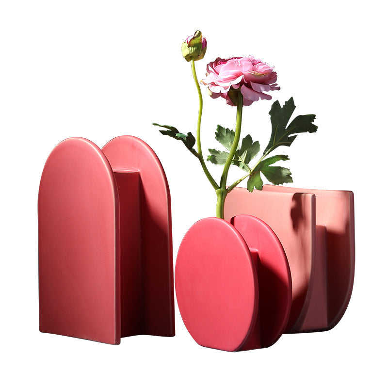 Pink geometric vase with a single pink flower on a white background