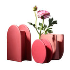 Pink geometric vase with a single pink flower on a white background