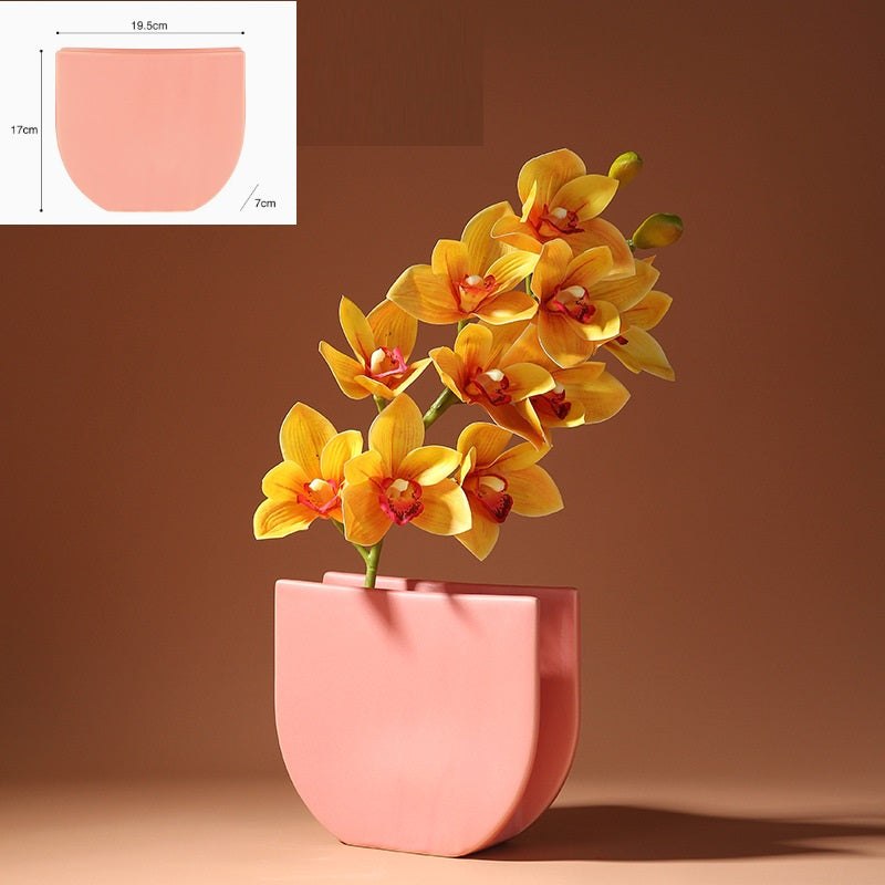 Pink planter with yellow flowers on a brown background