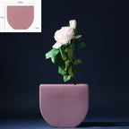 Pink planter with a white rose against a dark background