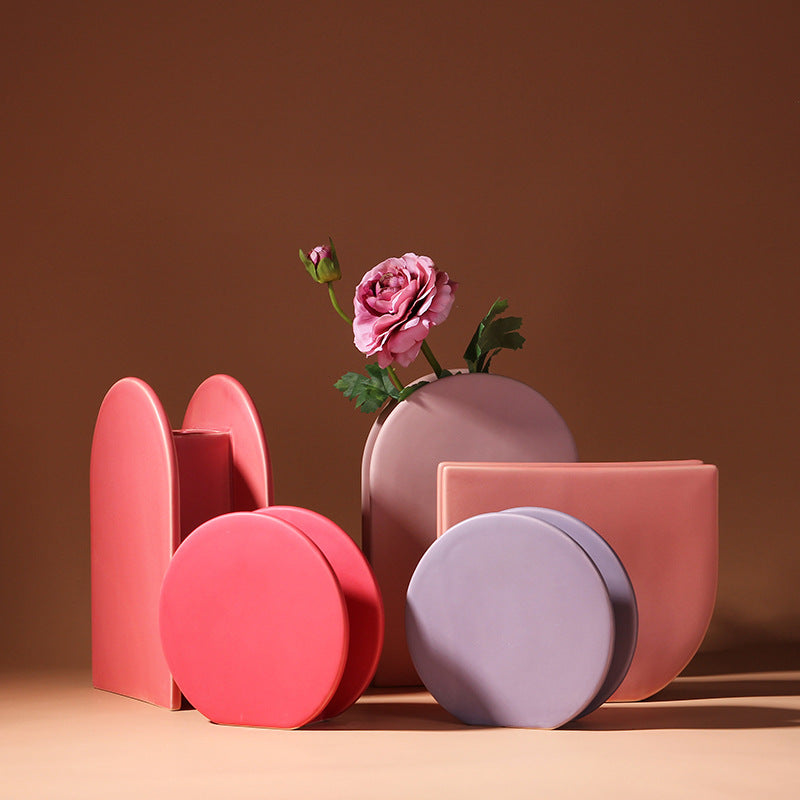 Set of colorful geometric vases with a pink rose on a brown background