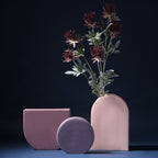 Three pink ceramic vases with a dark background