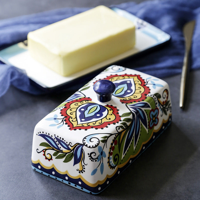 Decorative butter dish with a patterned lid on a blue cloth background