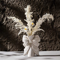 Bow knot ceramic vase styled with dried flowers in minimalist home decor setting