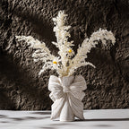 Bow knot ceramic vase styled with dried flowers in minimalist home decor setting