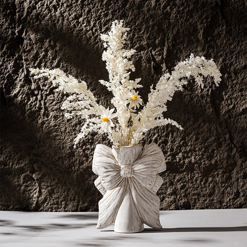 Bow knot ceramic vase styled with dried flowers in minimalist home decor setting