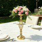 Gold decorative vase with pink flowers on a table outdoors
