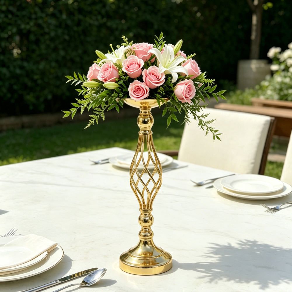 Gold decorative vase with pink flowers on a table outdoors