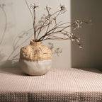 Decorative vase with wicker top and textured base on a textured surface